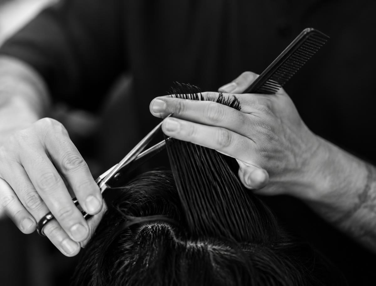 Hairdresser cutting hair with scissors and comb